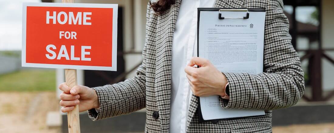 Real estate agent holding for sale sign by Thirdman