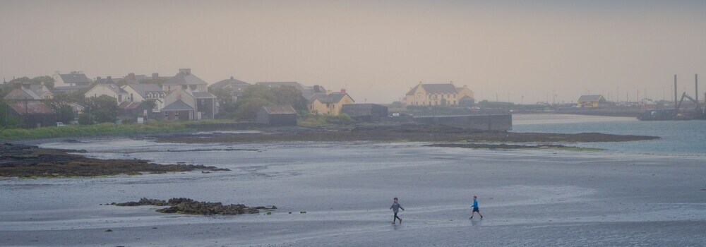 Two children play on a misty beach in the Aran Islands by Gunnar Ridderström