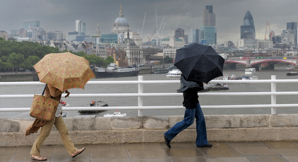 Two people with umbrellas brave the gloomy weather in London, UK