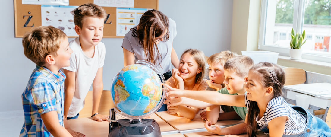 children and teacher interacting with a globe