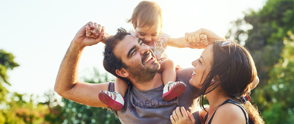 Joyful father and mother with baby on father's shoulder